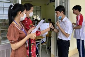 Hình ảnh cô giáo kiểm tra dụng cụ và giấy thi cho học sinh